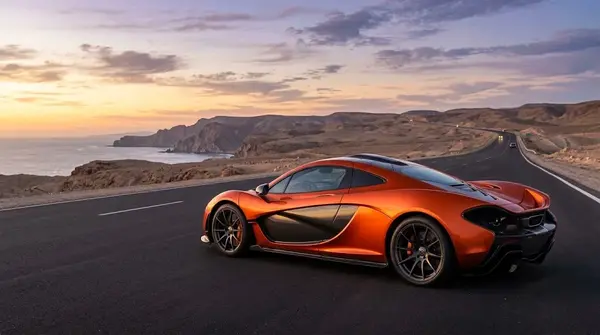 Sleek McLaren supercar parked on a scenic road showing aerodynamic body design.